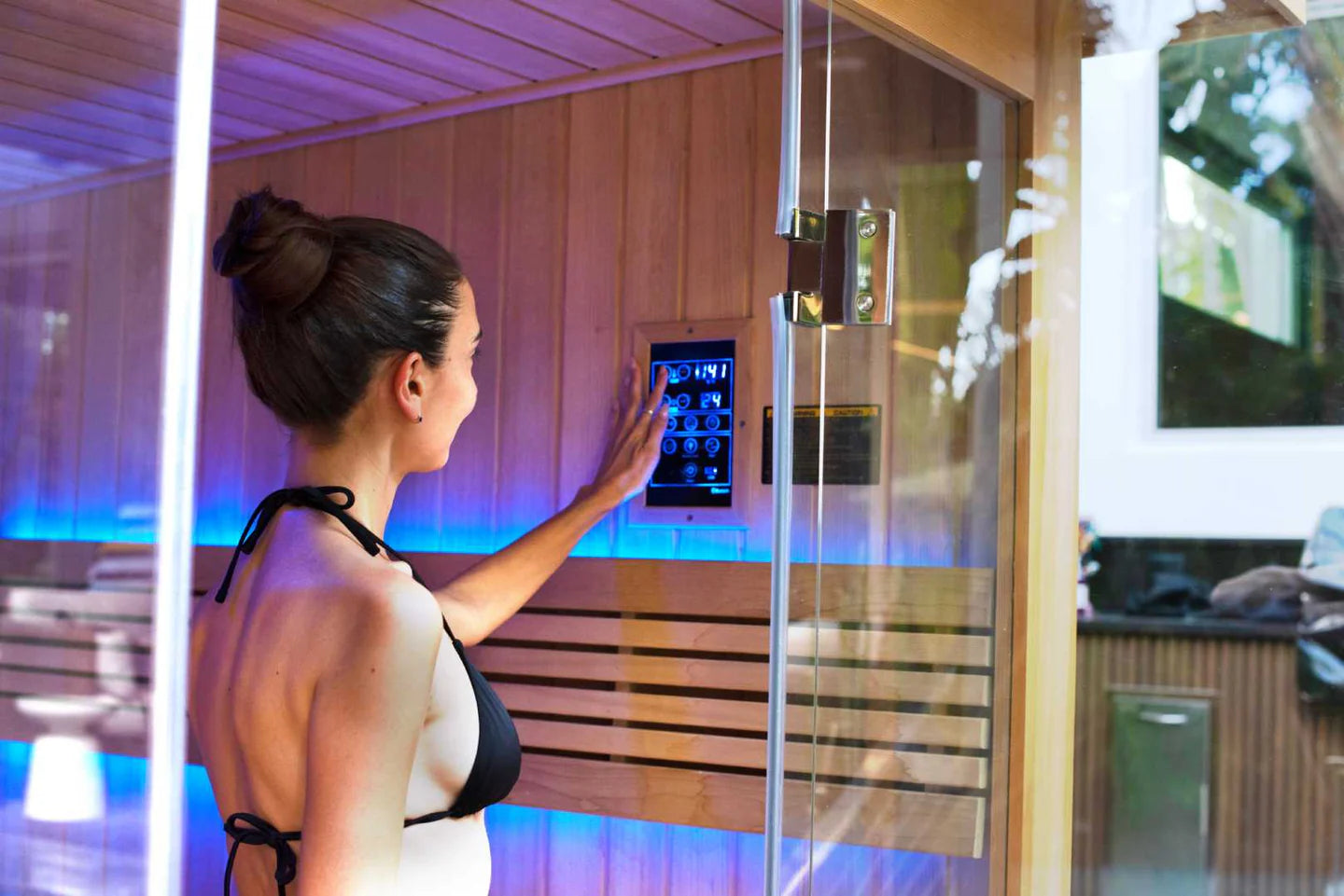 Woman using a control panel in a modern sauna with digital display.