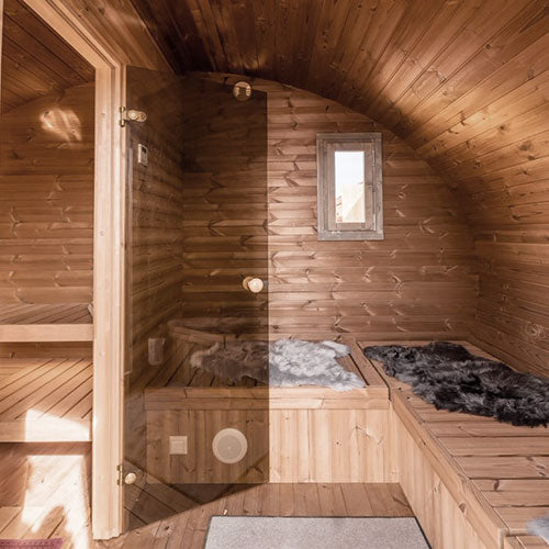 Wooden sauna with wooden walls and floor, featuring a small window and benches.