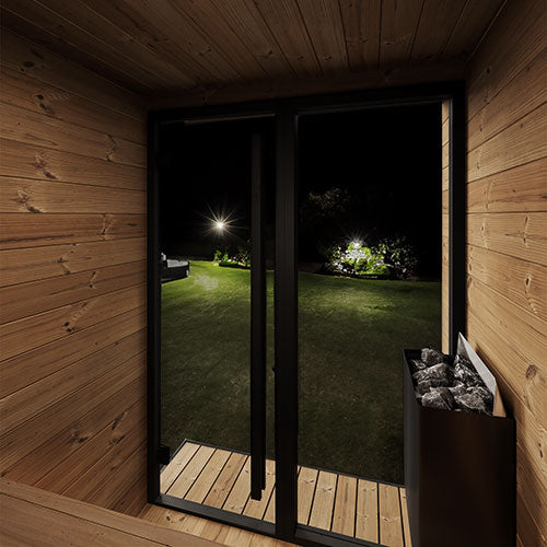 Wooden cabin interior with a view of a garden at night