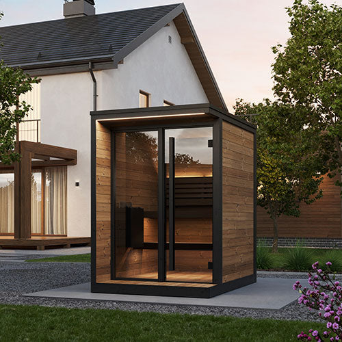 Modern outdoor sauna with wooden exterior and glass doors, set against a house and garden backdrop.