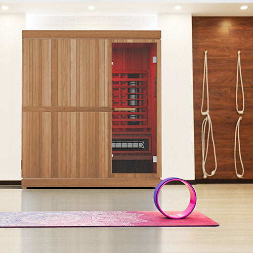 Infrared sauna with a yoga wheel and mat on a light wood floor.