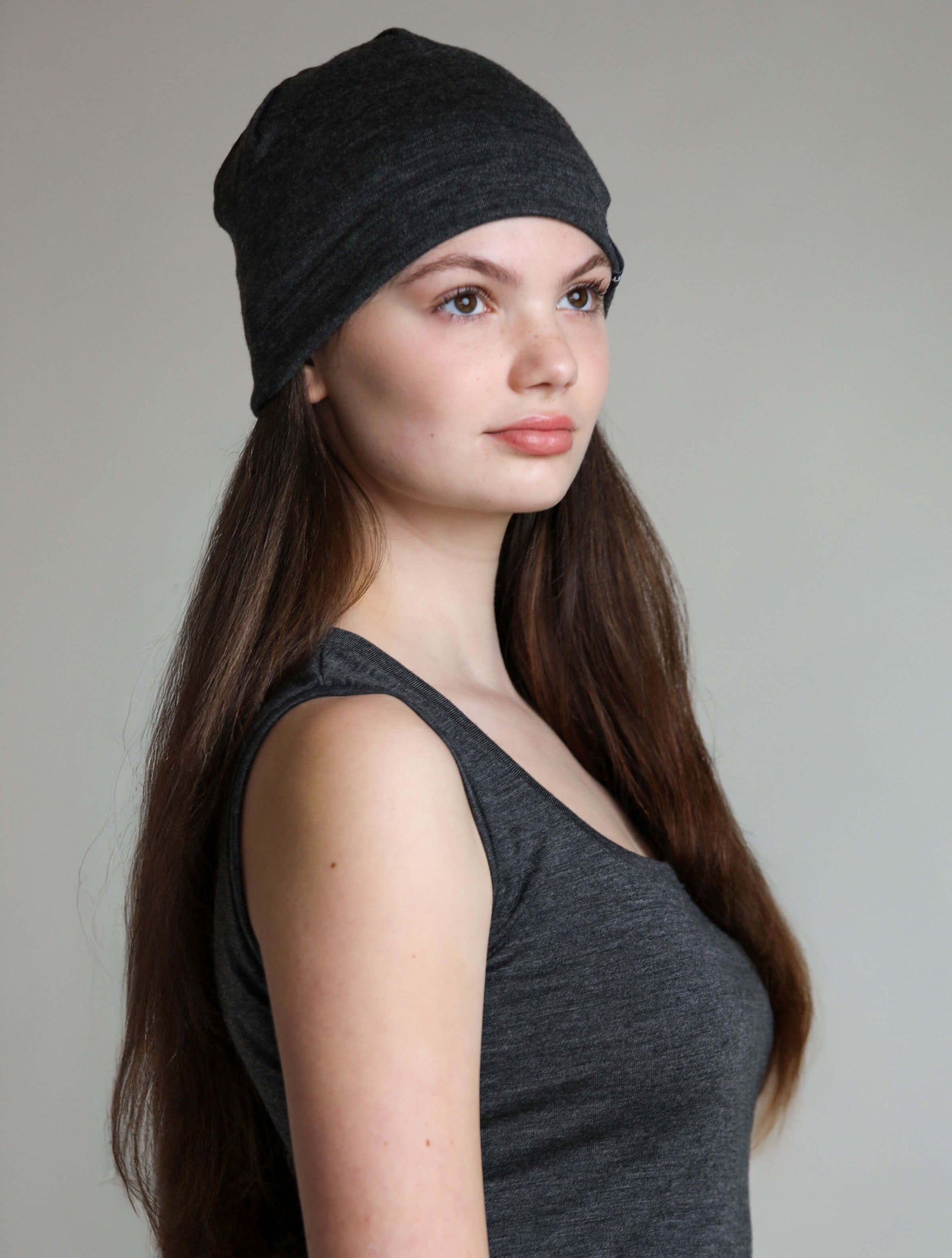 Woman wearing a grey beanie against a plain background