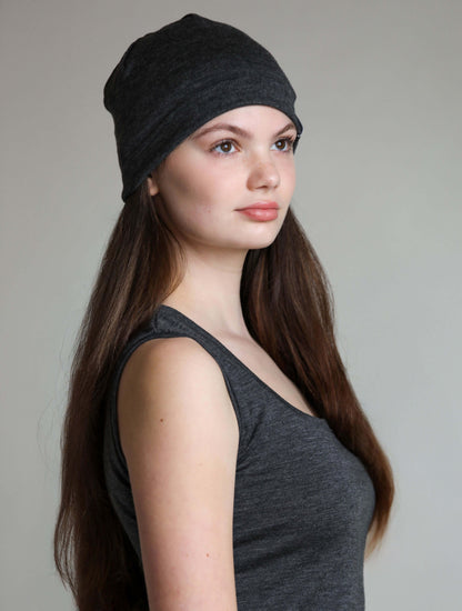 Woman wearing a grey beanie against a plain background